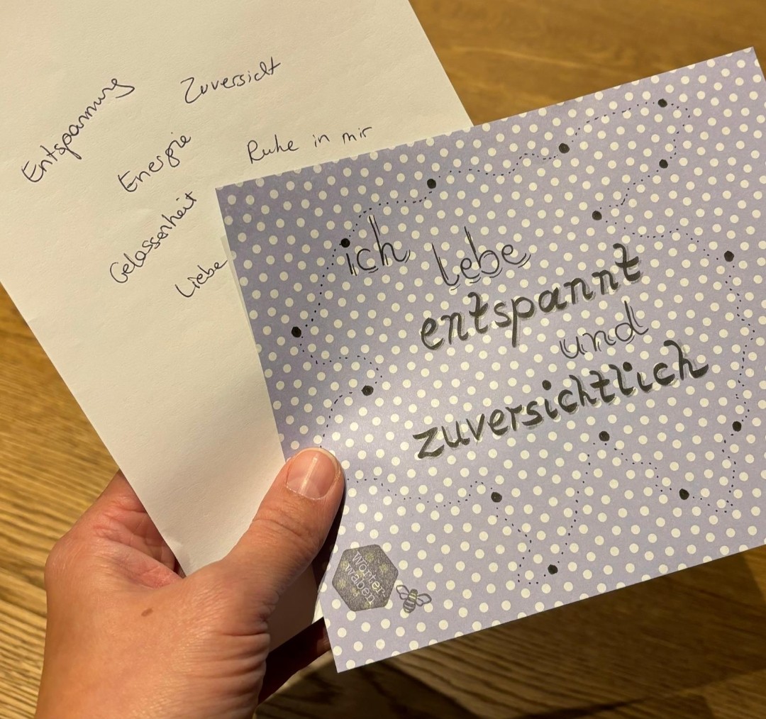 Zwei Karten mit handgeschriebenen Begriffen und Affirmation „Ich lebe entspannt und zuversichtlich“ in der Hand.